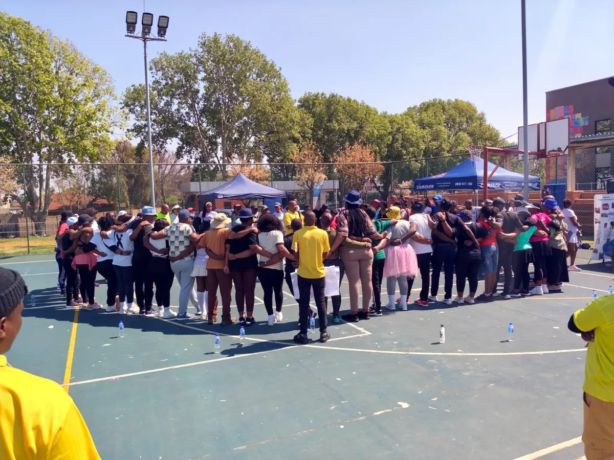 A team standing in a large circle during an outdoor team building session