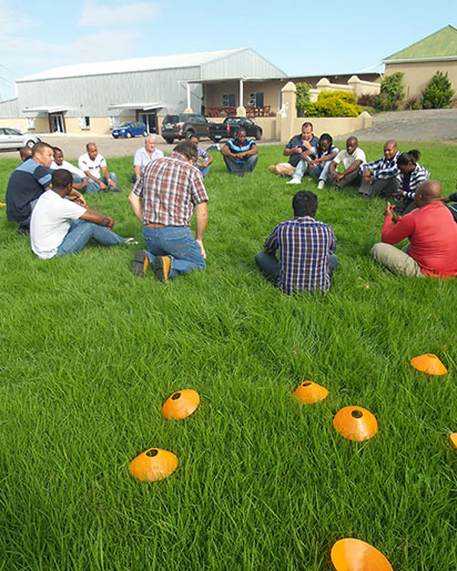 Outdoor team building session with delegates seated in groups on a lawn